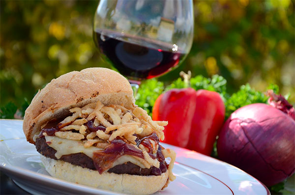 A plate with a gourmet hamburger and glass of red wine