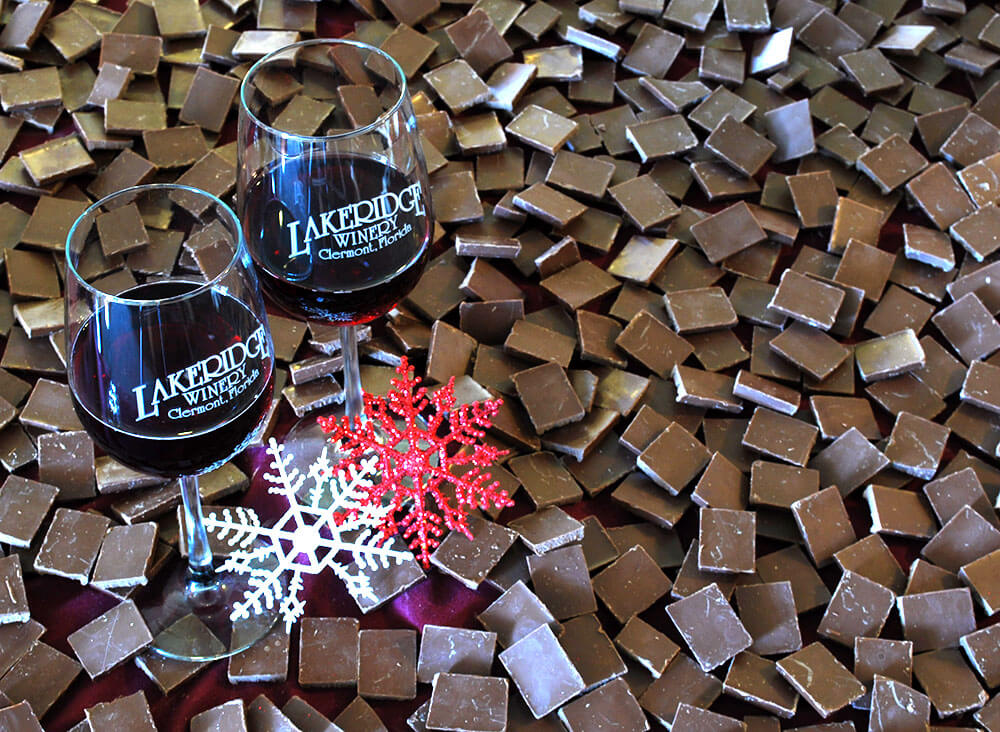 Two glasses of red wine on a table covered with chocolate and snow flake decorations