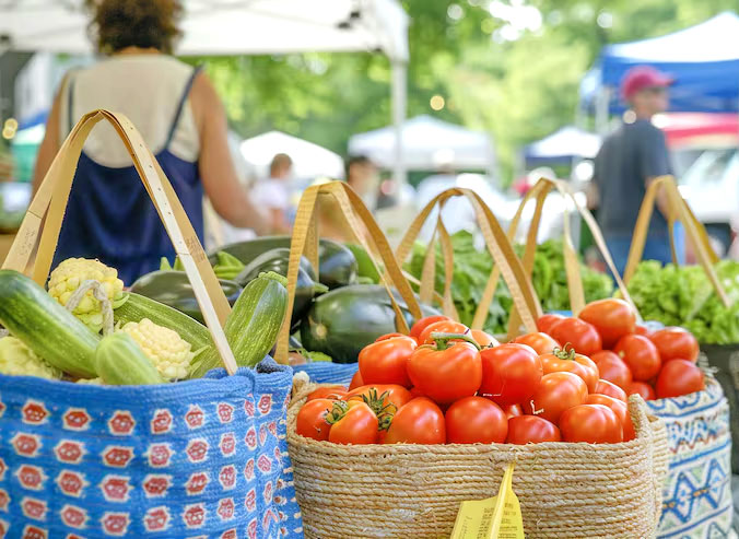 Bags of tomatoes and other produce at an outdoor farmers market.